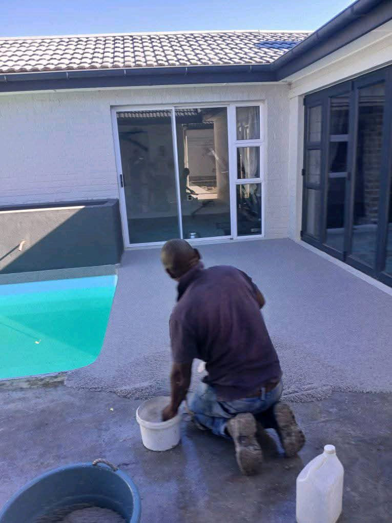 Installer applying quartz carpet around swimming pool